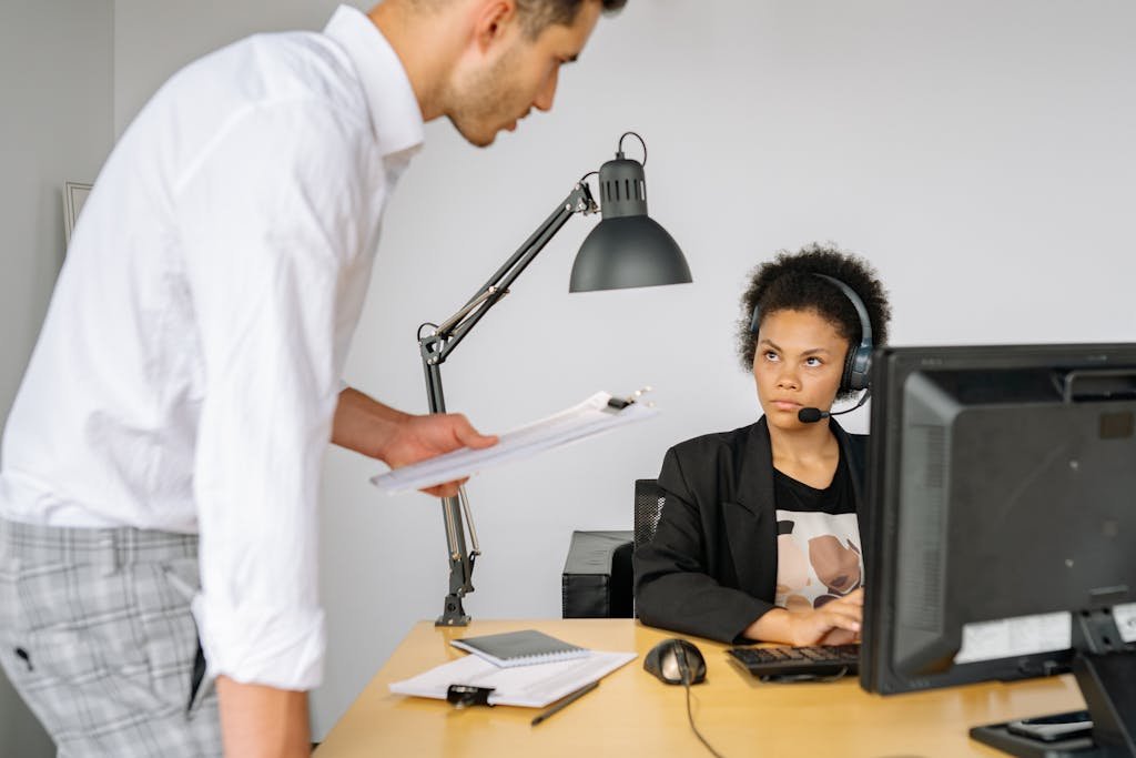 A man discusses work with a woman in a call center office setting.
