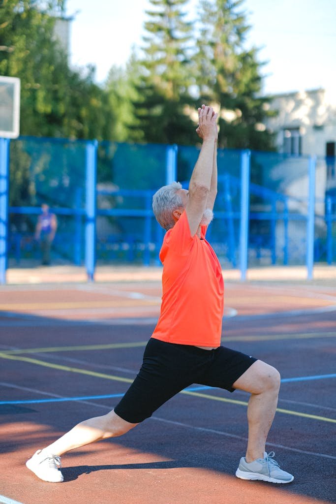 Elderly man in yoga warrior pose outdoors, focusing on fitness and wellness.