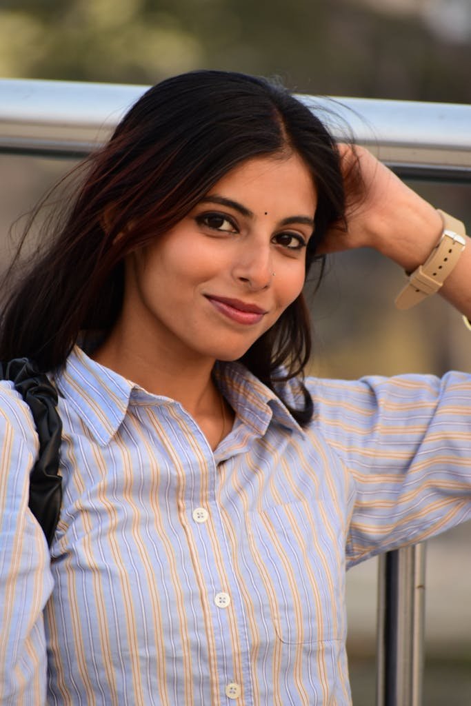 A young woman smiles confidently outdoors, showcasing casual fashion and natural beauty.