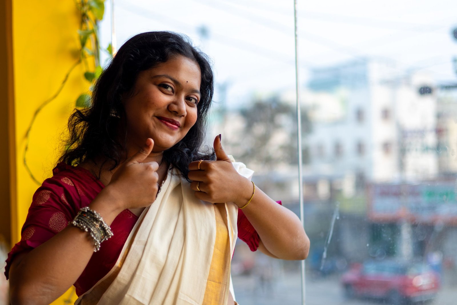 Happy South Asian woman in traditional saree giving thumbs up indoors in Bhubaneswar, India.