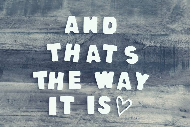 Wooden letters spell 'And that's the way it is' on rustic wood with a heart symbol.