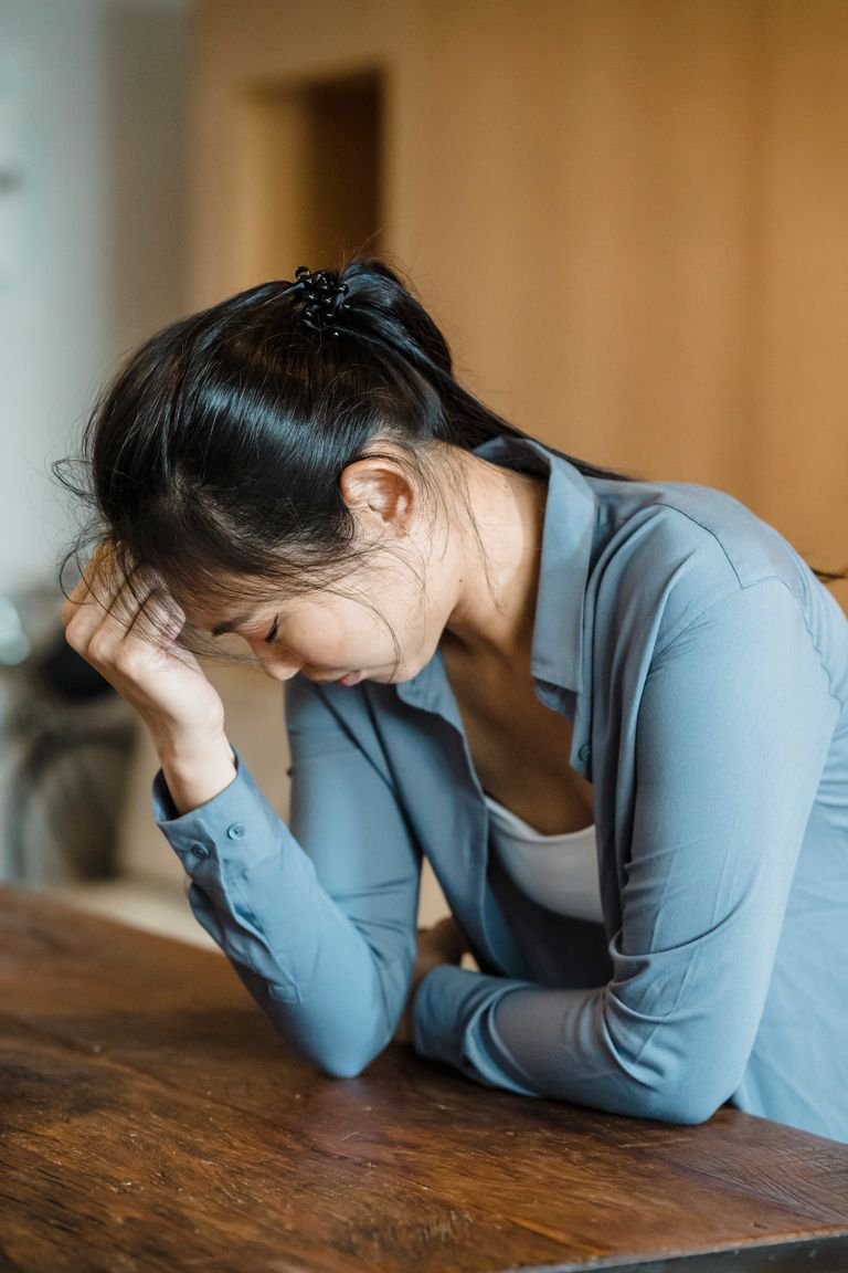 Young woman feeling stressed and upset indoors, resting head on hand.